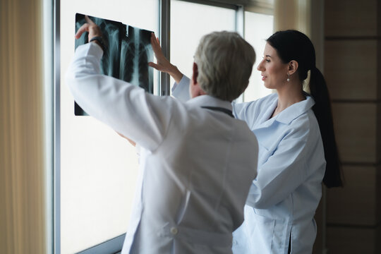 Caucasian male and female doctor in white gown discuss together with x-ray image of lung in hospital hallway. Health care concept of hospital industry after Covid-19 pandemic. 