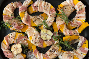 pumpkin with bacon, rosemary and garlic on a baking sheet close-up