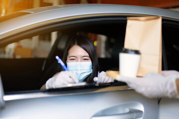 Woman sign for delivery food in car,Safety food during coronavirus pandemic situation,Drive thru service
