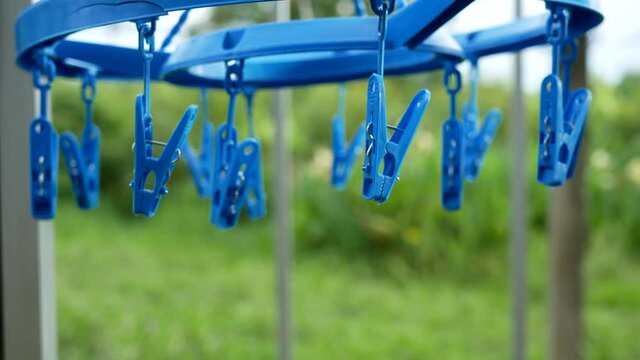 plastic cloth hanger with clothes pegs hanging on clothesline.