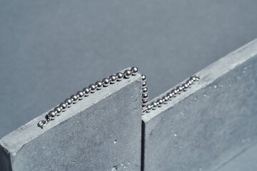 Close up shot of silver metal ball necklace on concrete element isolated over gray background