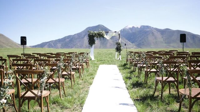 Empty wedding venue in outdoor meadow with mountains in background. First.person pov