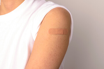 Forearm of a person with a sticking plaster on a white background