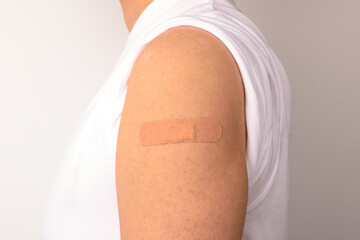 Forearm of a person with a sticking plaster on a white background