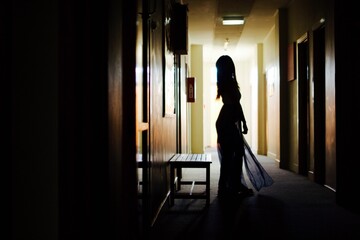 Silhouette of a girl in a long dress dancing at the end of the perspective corridor in New Zealand.