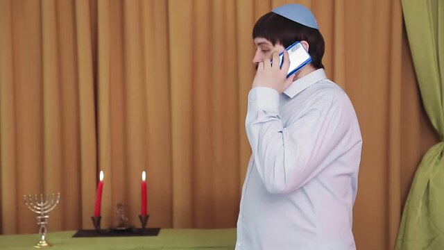 Before the chuppah ceremony, the Jewish groom speaks on the phone in the synagogue hall.