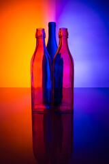 Still life with colored glass bottles on a colored background