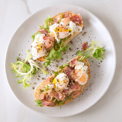 flat lay plate of poached quail egg sandwiches and bacon on marble table, square