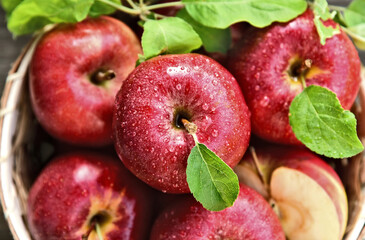 A lot of fresh Royal Red Gala apples with green leaf and water drop in basket on wooden background.