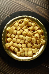 Delicious homemade garlic ,butter chakli, murukku served in brass plate, Indian savory snack foods.