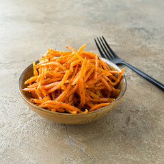 a bowl of Korean-style pickled carrots on a beige table