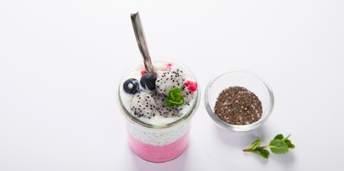 Layered chia puding with pink filling on white background.