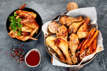 Roasted chicken legs with garlic and sauce on gray background.