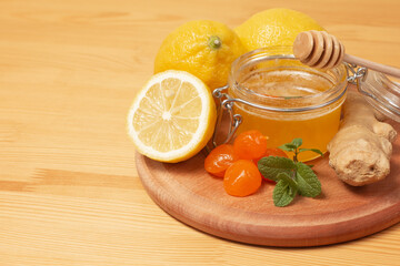 Ginger root, mint, lemon and liquid honey in honey-jar. Wooden background. Healthy food. Selective focus.