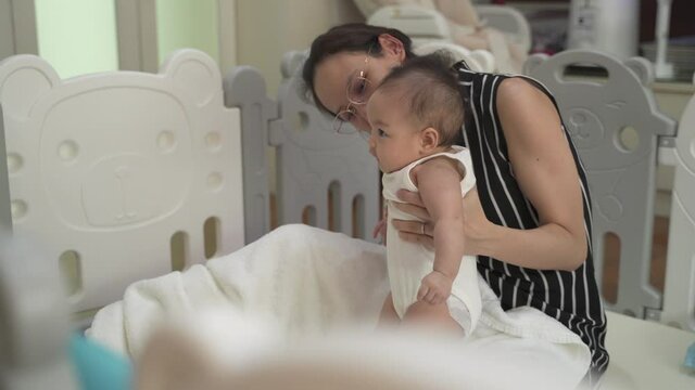 asian baby infant learning walking skill development by mother woman encourage at home. parent mother assist helping baby standing lesson. authentic life at home. baby infant playing in playpen. stand