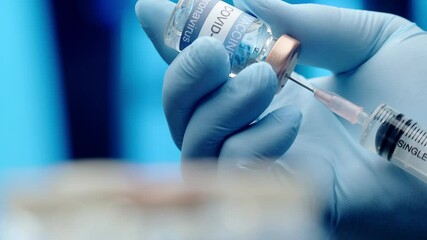 A doctor or nurse wearing latex gloves fills a syringe with the COVID vaccine - isolated close up - Powered by Adobe