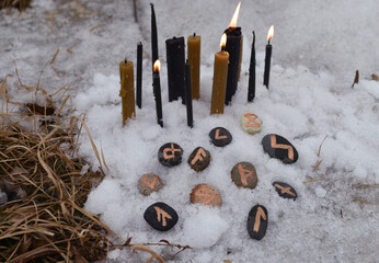 Burning candles and runes in snow outside.