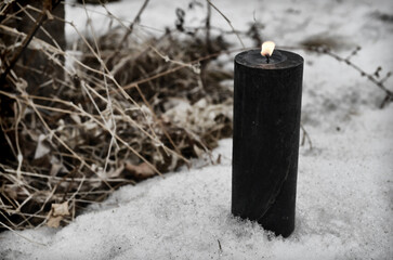 Single black candle outside in winter, grunge style.