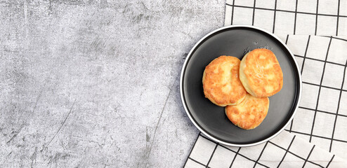 Cottage cheese pancakes on a round plate on a dark grey background. Top view, flat lay