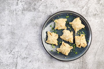 Manti - asian steam meat dumplings on a round plate on a dark grey background. Top view, flat lay