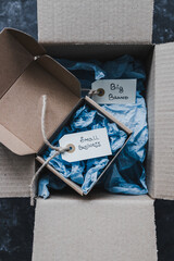 product tags with small business vs big brand texts inside of bigger and smaller delivery parcels,...
