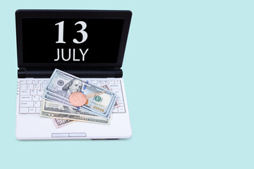 Laptop with the date of 13 july and cryptocurrency Bitcoin, dollars on a blue background. Buy or sell cryptocurrency. Stock market concept.