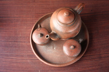 kettles and glasses handmade with clay materials. traditional Javanese kitchen tools used for warm drinks. Indonesian red kitchen utensil on a wooden background