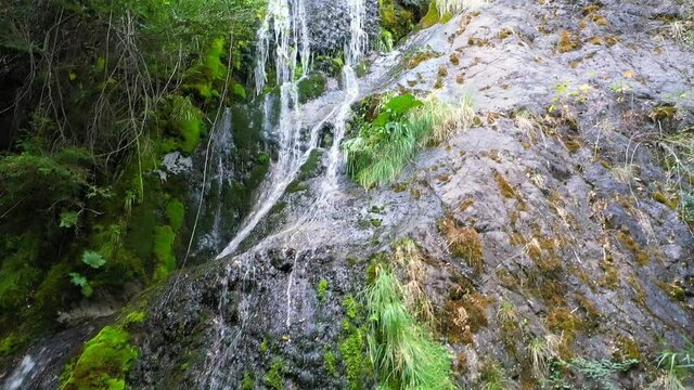 Drone films fine waterfall on the side of a rocky mountain that falls into the White River in Lago Puelo, Chubút, Patagonia Argentina.