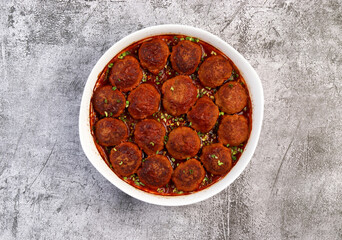 Homemade meatballs with tomato sauce in a white baking dish on a dark grey background. Top view, flat lay