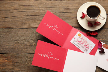 Gift cards and cup of coffee on wooden background