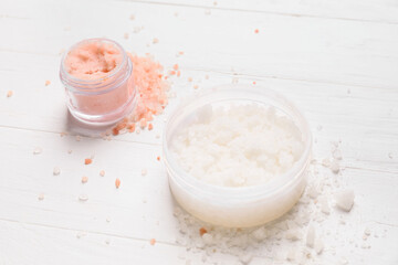 Jars of body scrub on light wooden background