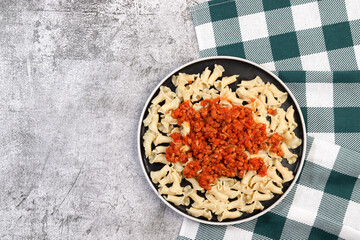 Traditional pasta bolognese on a round plate on a dark grey background. Top view, flat lay