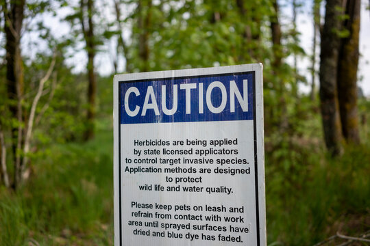 Caution sign informing visitors of herbicides being applied to control target invasive species in a nature park.