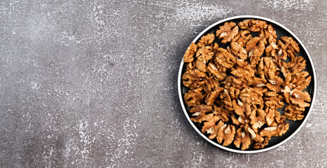 Walnuts on a round plate on a dark background. Top view, flat lay