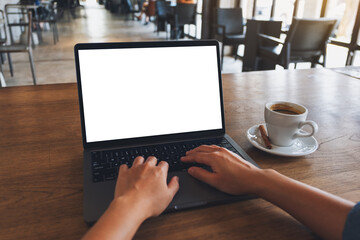 Mockup image of a woman using and typing on laptop computer with blank white desktop screen in cafe