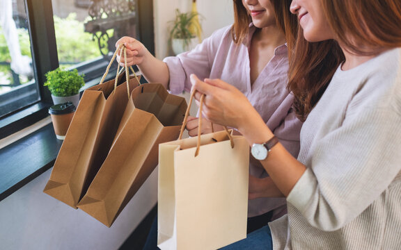 Closeup image of two young women opening and looking at shopping bags together