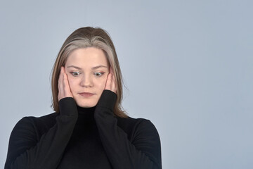 surprised young woman in a black sweater on the background, copy space, emotions
