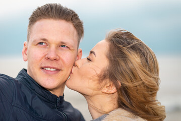 Beautiful young happy woman kissing and hugging boyfriend while taking selfie photo on sunny beach.Close up.