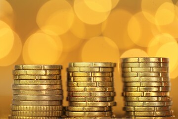 Money and finance concept.Coins columns in gold glitter on a golden background.Money growth.Money symbol. Wealth and success concept.Investments and savings