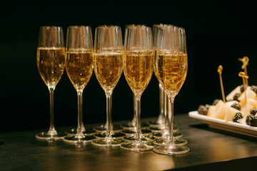 a row of glasses filled with champagne lined up ready to be served