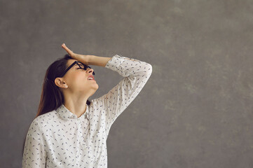Young caucasian woman touching forehead regrets wrong doing studio shot. Silly millennial slapping...