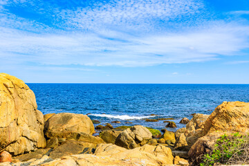 Fototapeta na wymiar Rock on the beach with beautiful clouds in tropical sea.