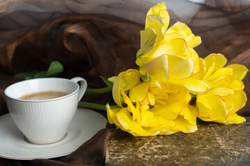 Still life. Yellow and orange tulips, cup of coffee and old book. Concept of congratulation