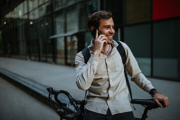 Fototapeta premium Businessman commuting to work with his bicycle and talking on phone
