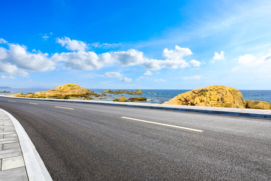 Asphalt road and beautiful seaside scenery under blue sky.