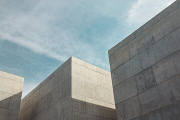 Modern construction detail. Concrete structure of straight lines with a blue sky background with clouds. Contrapicado plane.