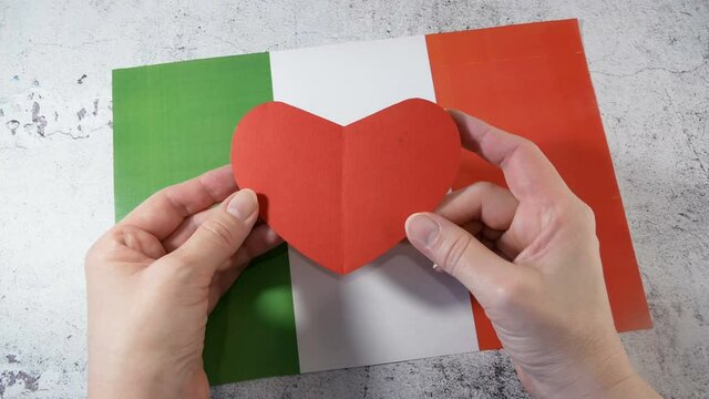I love Italy. Hands hold red heart symbol on Italian flag background. Festa della Repubblica, 2 june, italy day