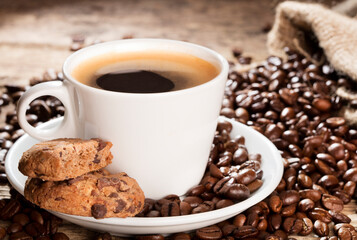 cup of coffee with cookies and beans on wooden background