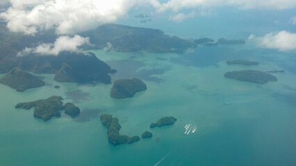 View from above on many green islands, sea and clouds. Aerial view of the islands Pulau Gubang Laut, Pulau Puchong, Pulau Tajai, Pulau Ajar, Pulau Gubang Darat, Pulau Dayang Bunting, Malaysia