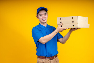 Young Asian handsome delivery man pointing to pizza boxs over yellow isolate background. Work from home and delivery concept.